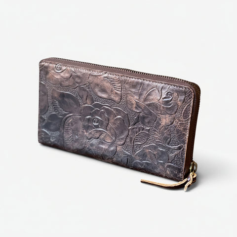 Brown leather wallet with floral embossing on a white background